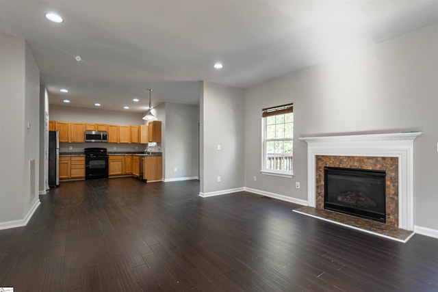 unfurnished living room featuring dark hardwood / wood-style flooring and a tiled fireplace