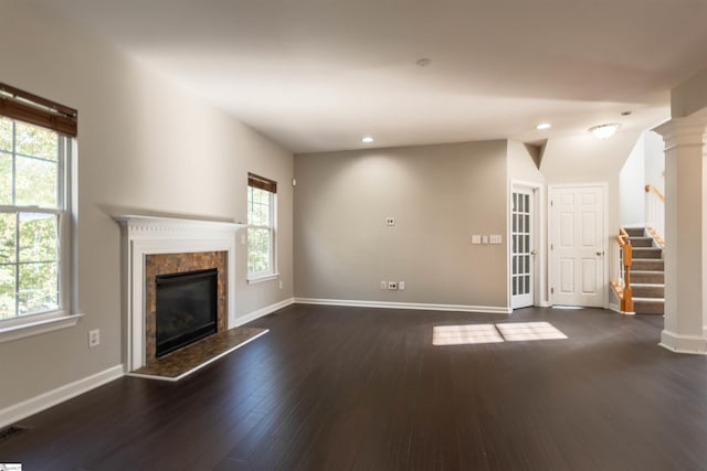 unfurnished living room featuring dark hardwood / wood-style flooring, a wealth of natural light, decorative columns, and a premium fireplace