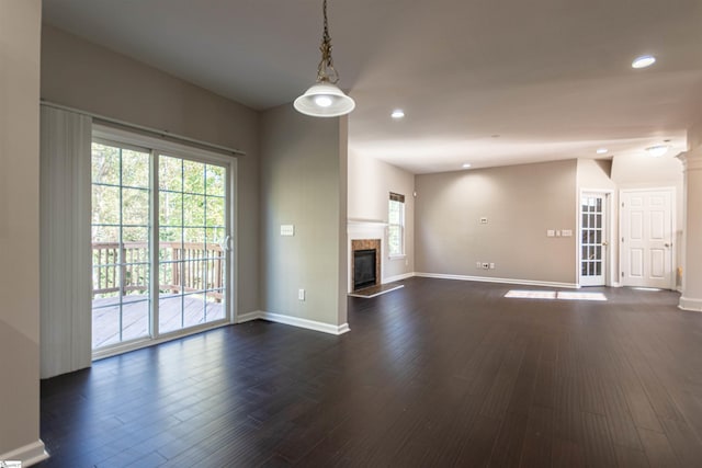 unfurnished living room with dark hardwood / wood-style flooring, a high end fireplace, and a wealth of natural light