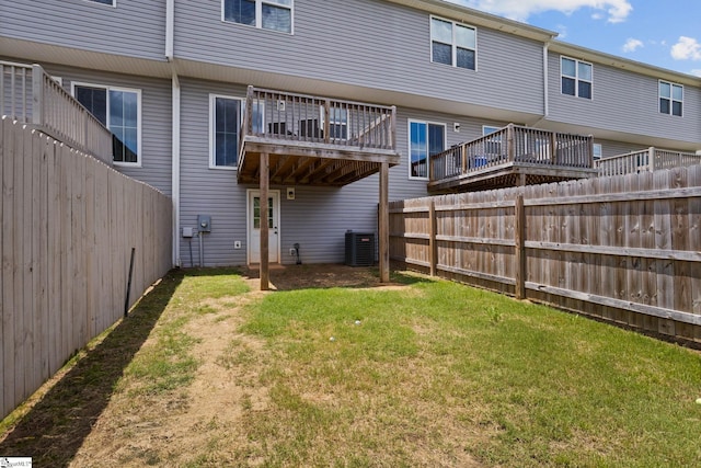 back of property with central AC unit and a lawn