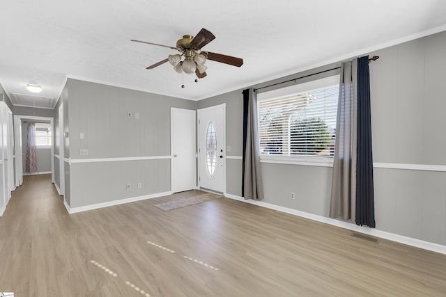 interior space with ceiling fan, ornamental molding, and light wood-type flooring