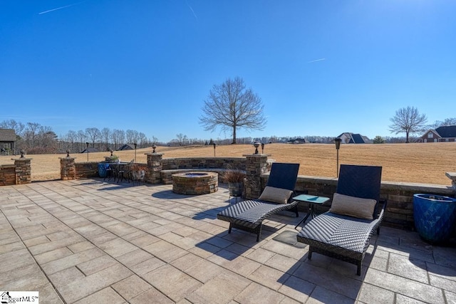 view of patio with a rural view and an outdoor fire pit