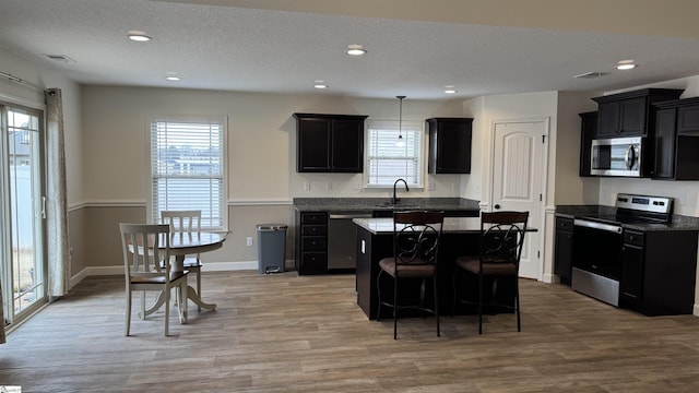 kitchen with sink, a breakfast bar area, a center island, appliances with stainless steel finishes, and a wealth of natural light