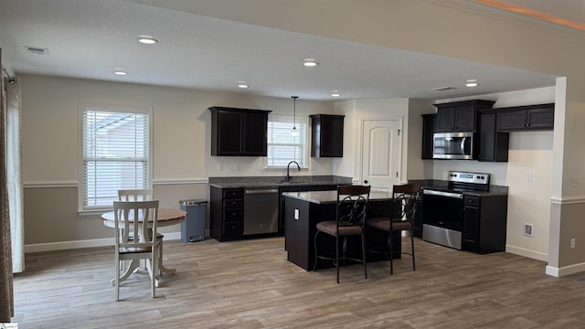 kitchen featuring plenty of natural light, stainless steel appliances, a center island, and a breakfast bar