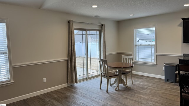 dining space with hardwood / wood-style floors and a textured ceiling