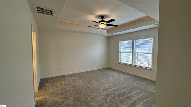 carpeted empty room featuring ceiling fan, ornamental molding, a tray ceiling, and a textured ceiling