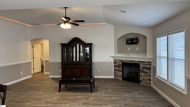 living room featuring lofted ceiling, a stone fireplace, dark hardwood / wood-style floors, and ceiling fan