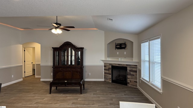 living area featuring a stone fireplace, hardwood / wood-style floors, lofted ceiling, and ceiling fan