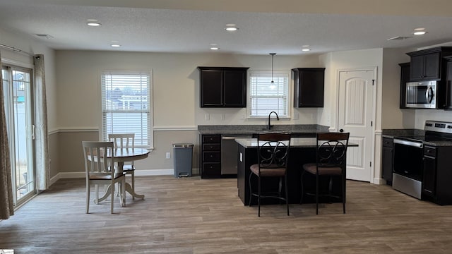 kitchen with a healthy amount of sunlight, appliances with stainless steel finishes, a kitchen island, and a textured ceiling