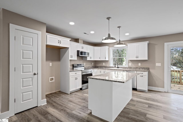 kitchen featuring white cabinetry, stainless steel appliances, a center island, and light stone countertops