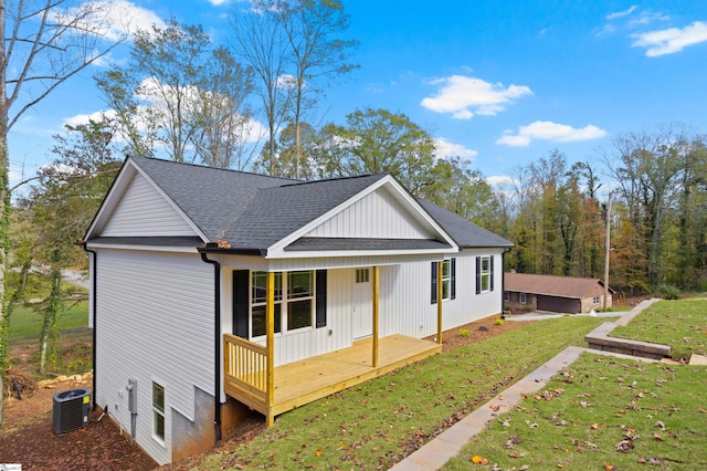 exterior space with a porch, cooling unit, an outbuilding, a garage, and a front lawn