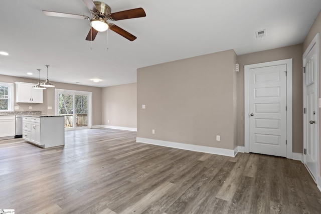 unfurnished living room featuring a wealth of natural light, ceiling fan, and light wood-type flooring