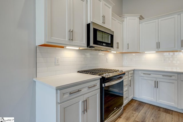 kitchen featuring white cabinetry, appliances with stainless steel finishes, backsplash, and light hardwood / wood-style flooring