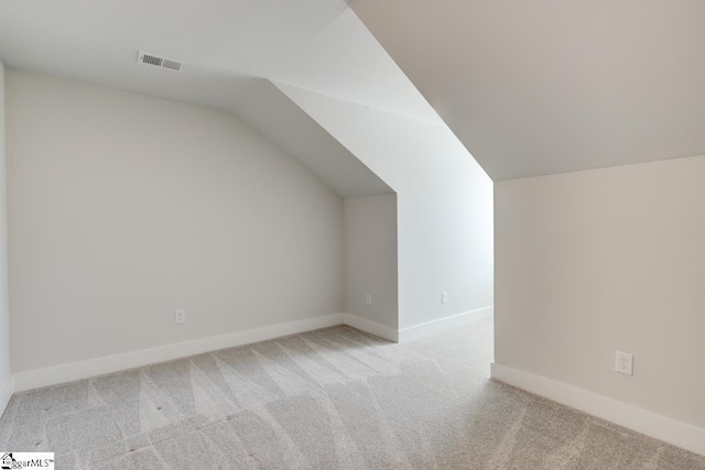 bonus room with vaulted ceiling and light carpet