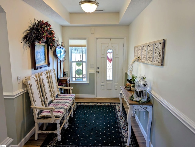 foyer entrance featuring a tray ceiling and hardwood / wood-style floors