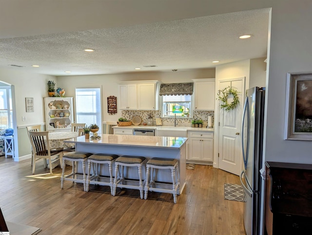 kitchen with white cabinetry, light hardwood / wood-style flooring, appliances with stainless steel finishes, a kitchen island, and backsplash