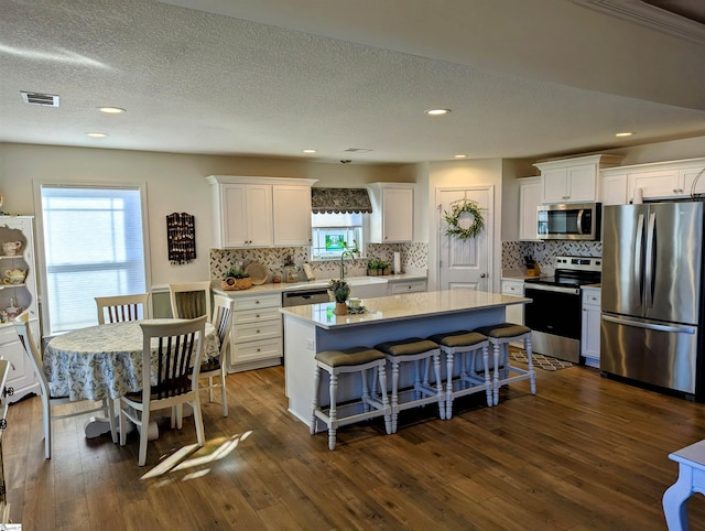 kitchen with white cabinetry, dark hardwood / wood-style flooring, stainless steel appliances, and a center island