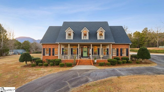 cape cod-style house with covered porch