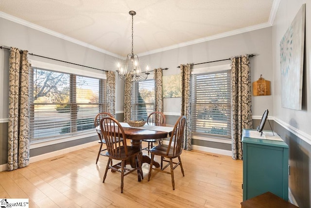 dining area with ornamental molding, an inviting chandelier, and light hardwood / wood-style flooring