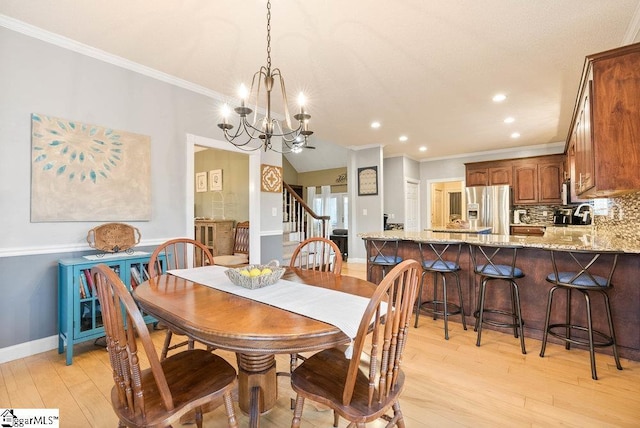 dining space featuring an inviting chandelier, crown molding, and light hardwood / wood-style floors