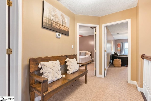 corridor featuring light carpet and a textured ceiling