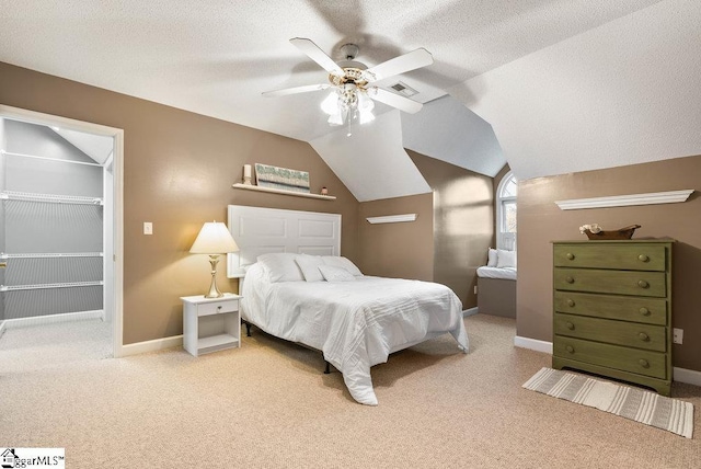 bedroom featuring lofted ceiling, a spacious closet, carpet, and a textured ceiling