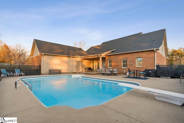 view of swimming pool featuring a patio area and a diving board