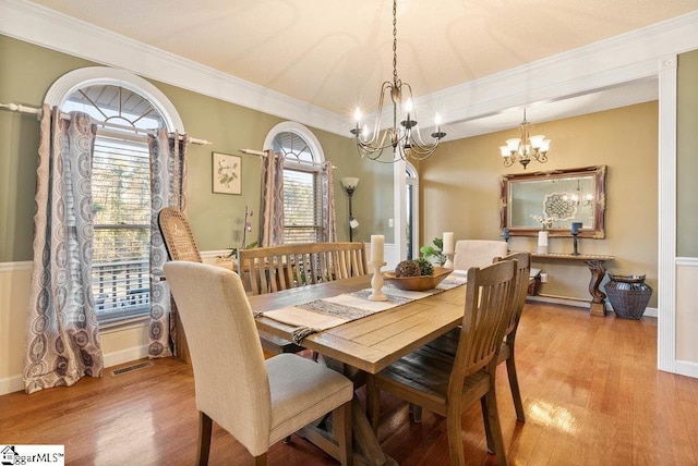 dining space with an inviting chandelier, crown molding, and light hardwood / wood-style floors