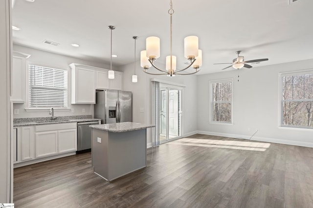 kitchen with white cabinetry, light stone counters, hanging light fixtures, a kitchen island, and stainless steel appliances