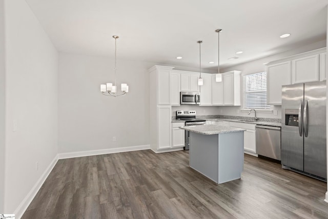 kitchen with dark wood-type flooring, decorative light fixtures, a kitchen island, stainless steel appliances, and white cabinets