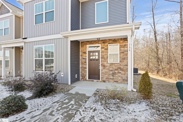 snow covered property entrance with central AC unit