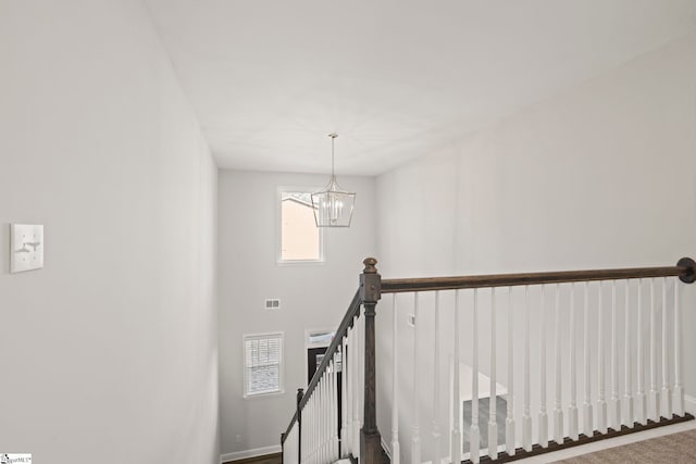 stairs with a notable chandelier and carpet floors