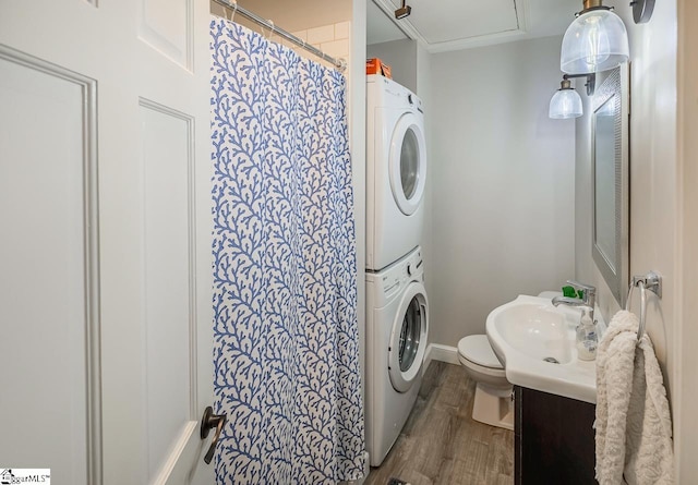 clothes washing area with sink, stacked washer / drying machine, and hardwood / wood-style floors