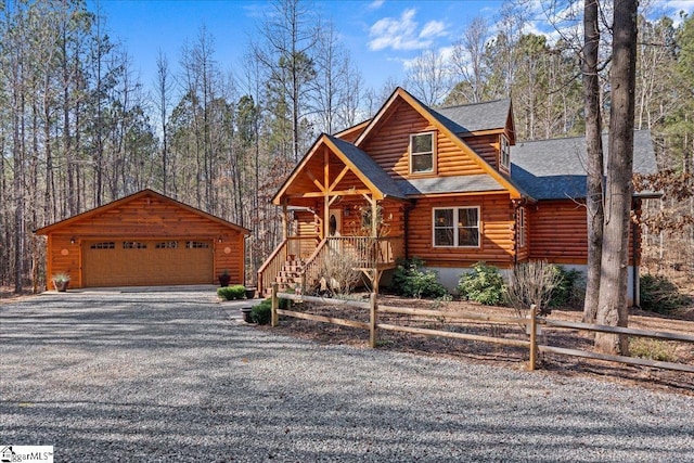 cabin with a shingled roof, fence, log siding, a garage, and an outdoor structure