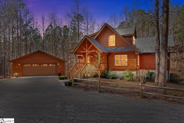 view of front facade with an outdoor structure, fence, a detached garage, roof with shingles, and log exterior