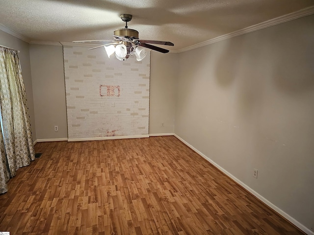 spare room featuring a textured ceiling, ornamental molding, hardwood / wood-style flooring, ceiling fan, and brick wall