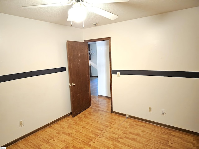 unfurnished room with ceiling fan, a textured ceiling, and light wood-type flooring