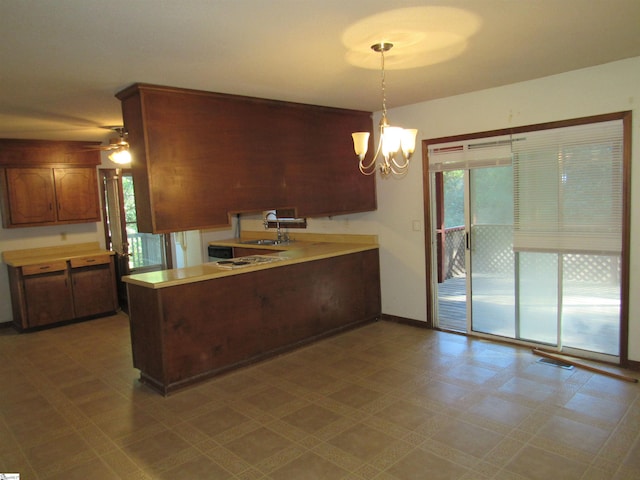 kitchen with pendant lighting, sink, kitchen peninsula, and a chandelier