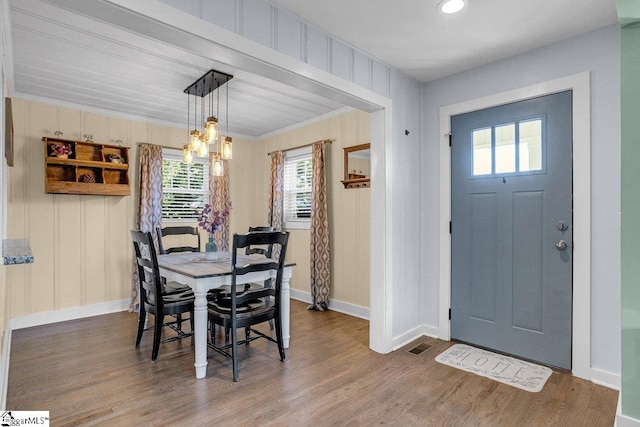 dining space with crown molding, wood-type flooring, and a notable chandelier