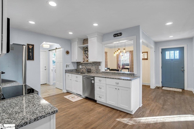 kitchen with sink, appliances with stainless steel finishes, white cabinetry, light hardwood / wood-style floors, and a barn door