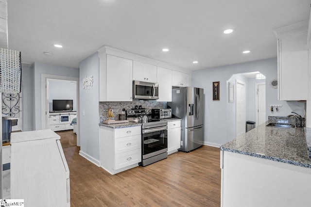 kitchen with sink, light hardwood / wood-style flooring, white cabinetry, stainless steel appliances, and tasteful backsplash