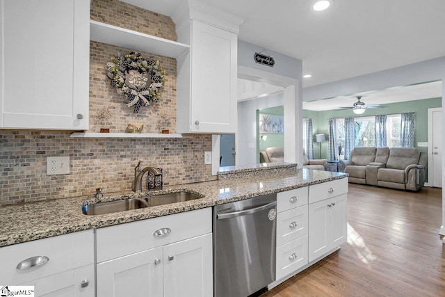 kitchen with sink, white cabinetry, light stone counters, light hardwood / wood-style floors, and stainless steel dishwasher