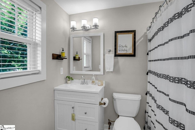 bathroom featuring a shower with curtain, vanity, a healthy amount of sunlight, and toilet