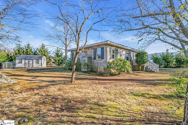 view of side of home with a lawn and a storage unit