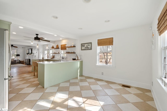 kitchen featuring stainless steel refrigerator, ceiling fan, plenty of natural light, and kitchen peninsula