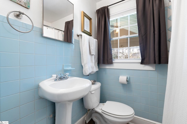 bathroom featuring tile walls and toilet