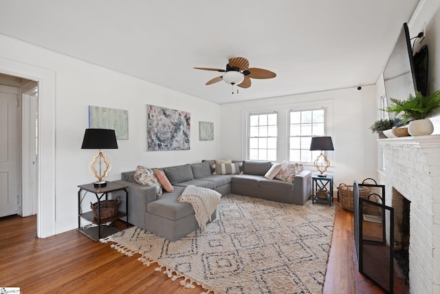 living room with ceiling fan, wood-type flooring, and a fireplace