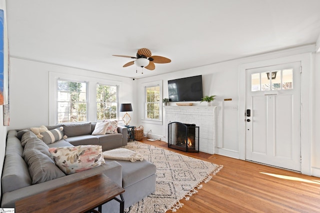 living room with a fireplace, light hardwood / wood-style floors, and ceiling fan