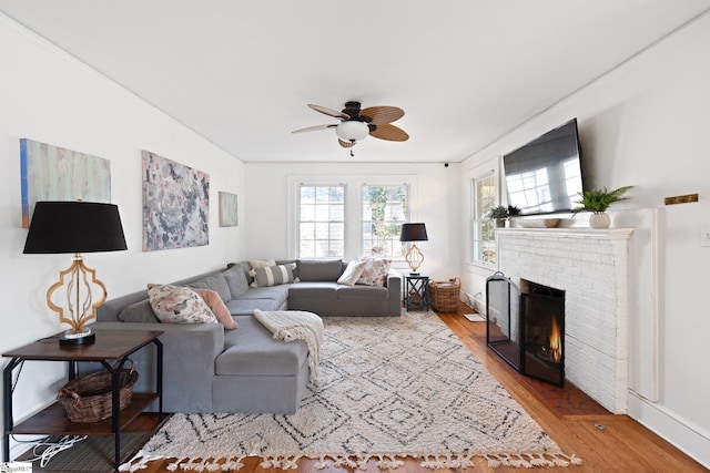 living room with a fireplace, light hardwood / wood-style floors, and ceiling fan