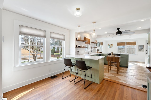 kitchen featuring a breakfast bar area, kitchen peninsula, light hardwood / wood-style floors, and hanging light fixtures